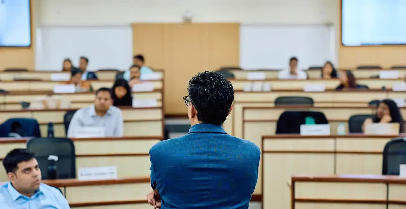 A facilitator standing before a cohort in a tiered classroom
